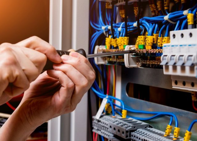 The man is repairing the switchboard voltage with automatic switches. Electrical background